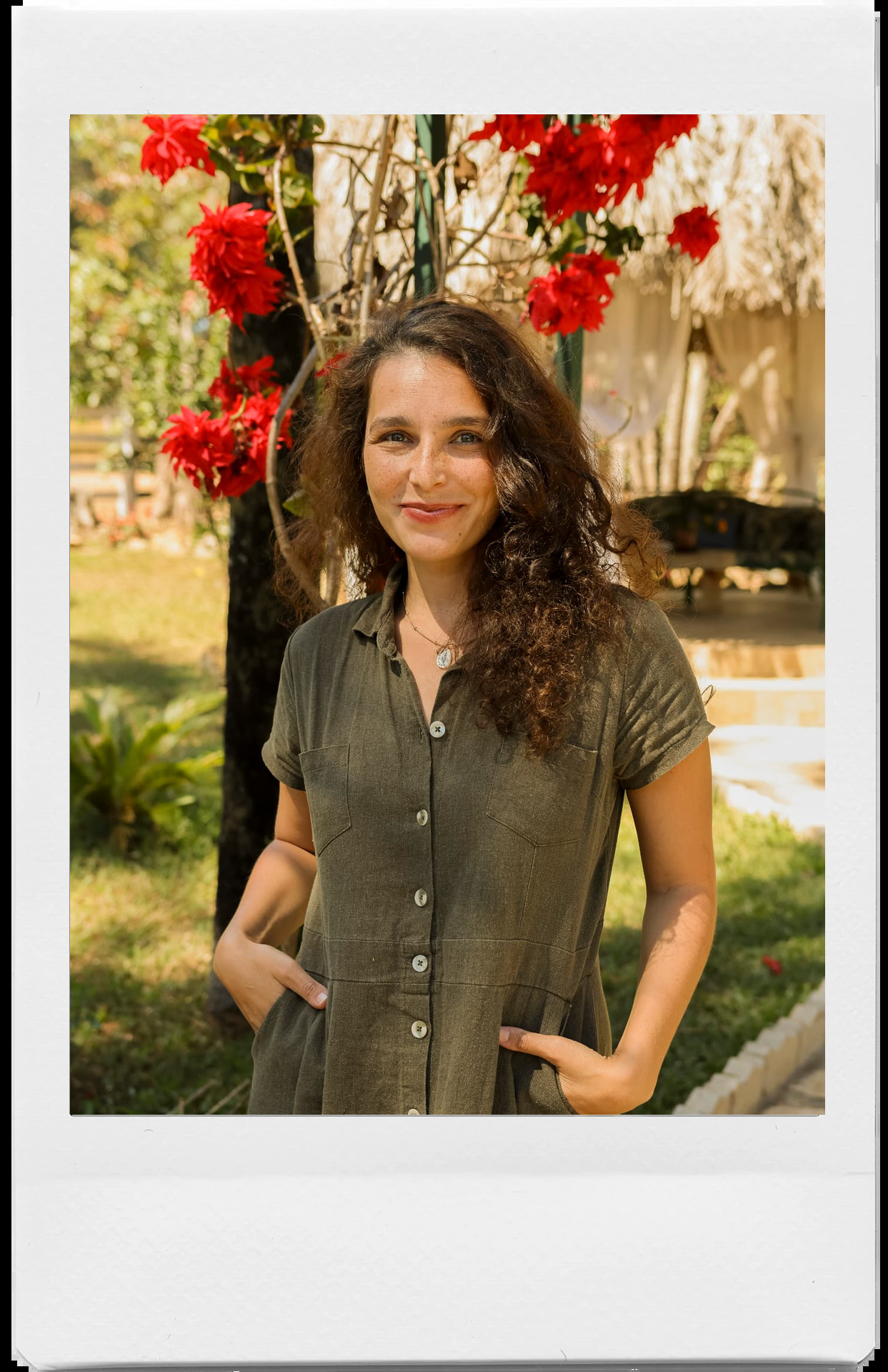 Yna Marson em um jardim com flores vermelhas ao fundo, em moldura polaroid